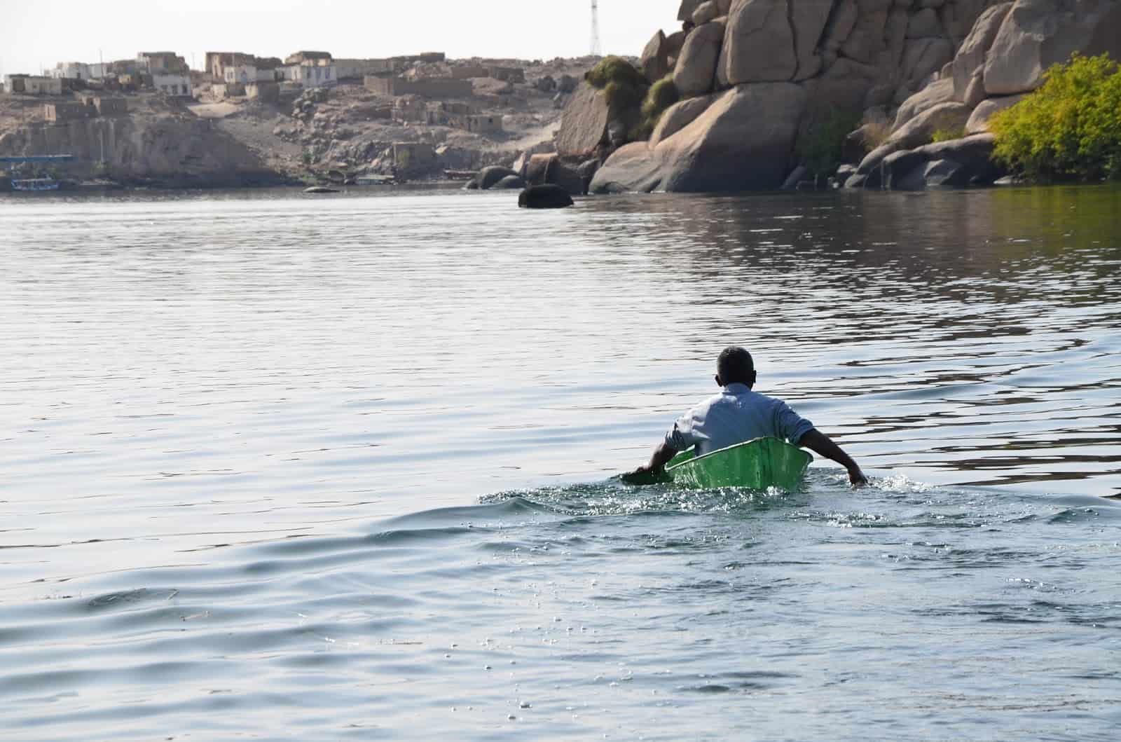 A man paddling away from the island at Philae Temple on Agilkia Island, Egypt
