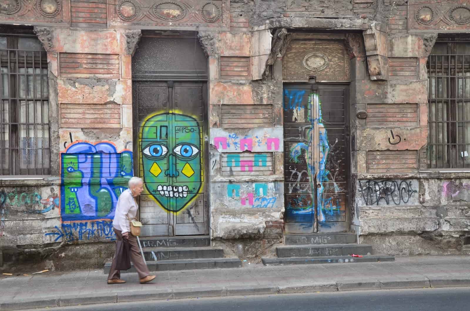 A woman walking past graffiti on Calle Compañía de Jesús in Barrio Yungay, Santiago de Chile