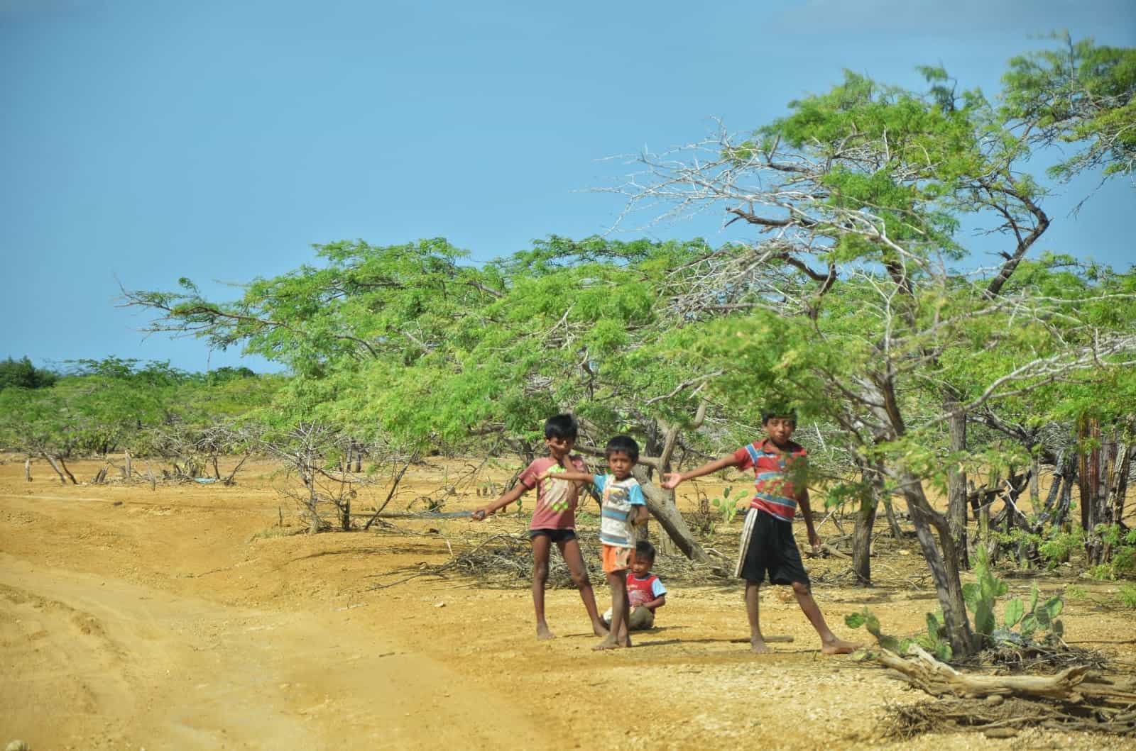 Wayúu children holding a rope across the road in La Guajira, Colombia
