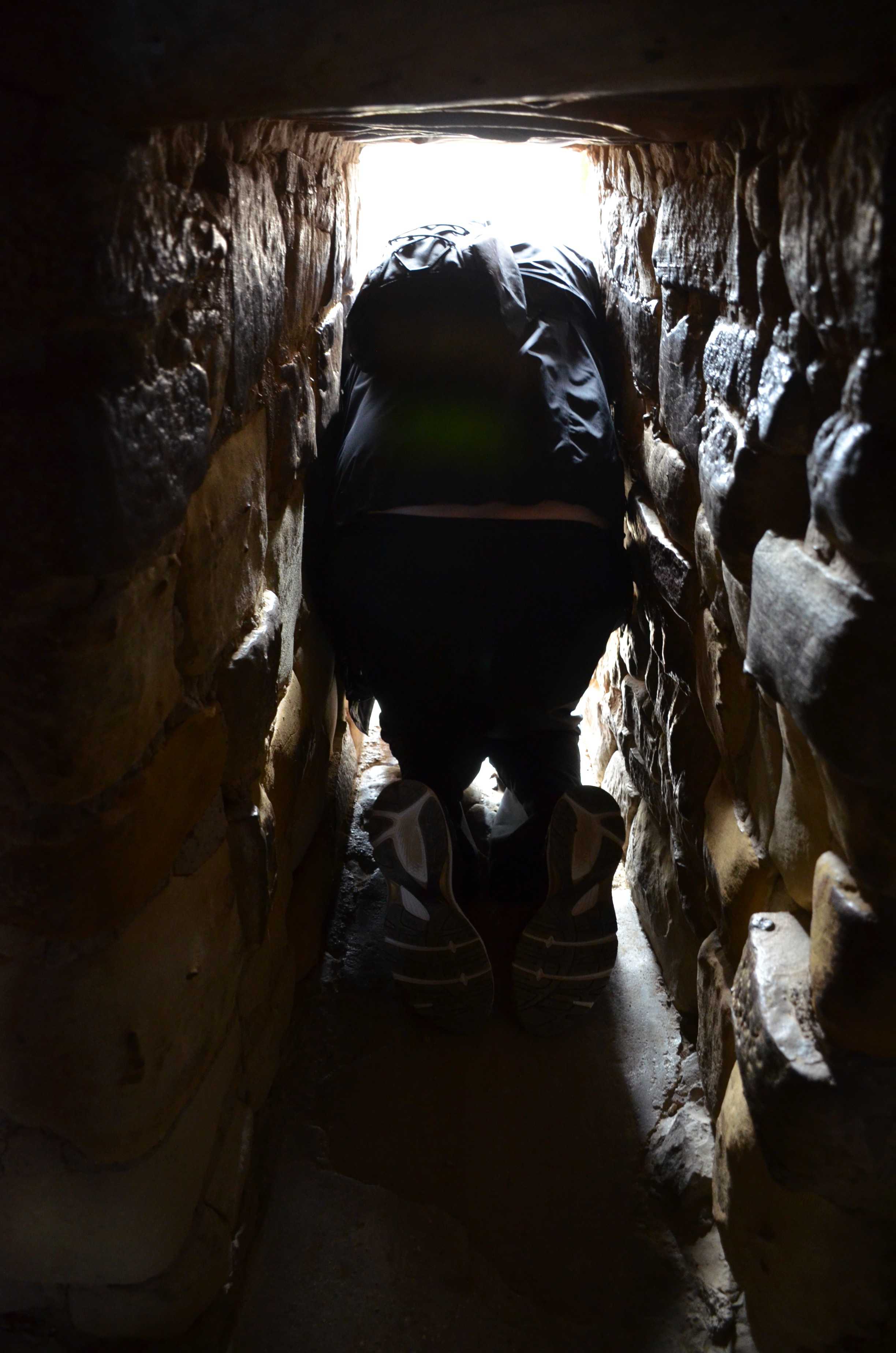 Squeezing through the tunnel on the Balcony House tour at Mesa Verde National Park in Colorado