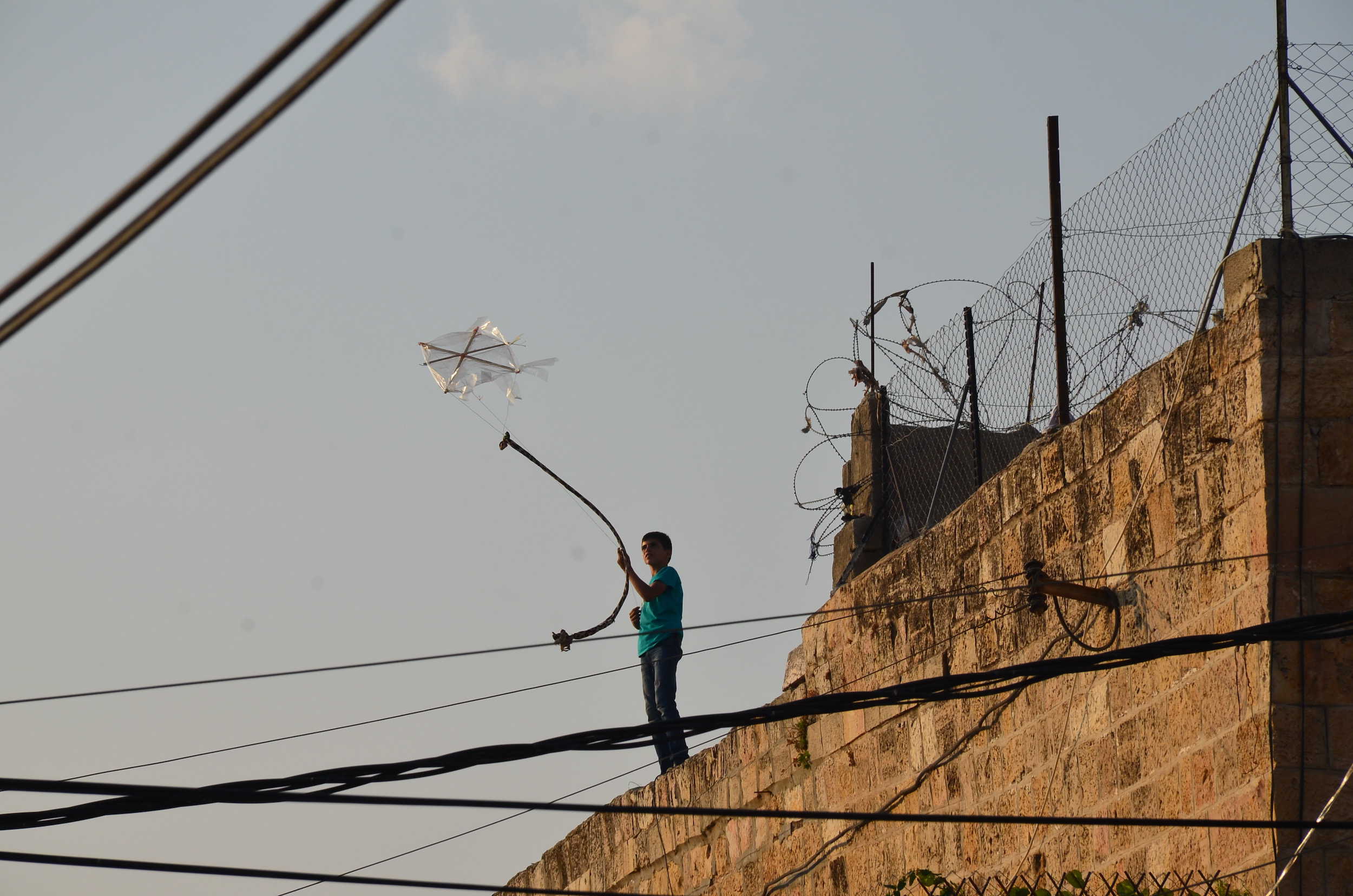 Boy flying a kite on a rooftop in the Old City in Hebron, Palestine