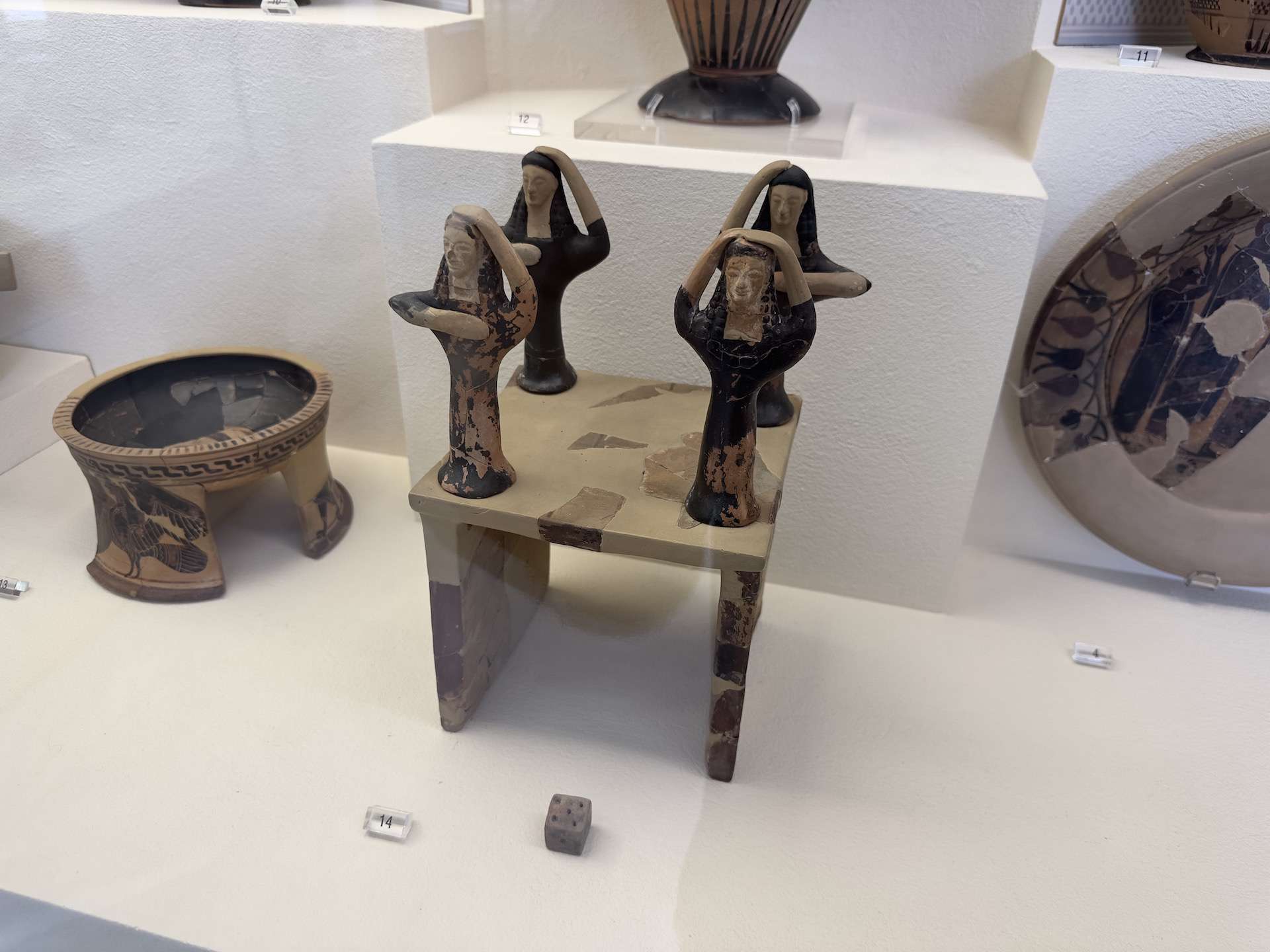 Miniature gaming table with four figurines of mourners and dice; c. 580 BC at the Kerameikos Museum in Athens, Greece