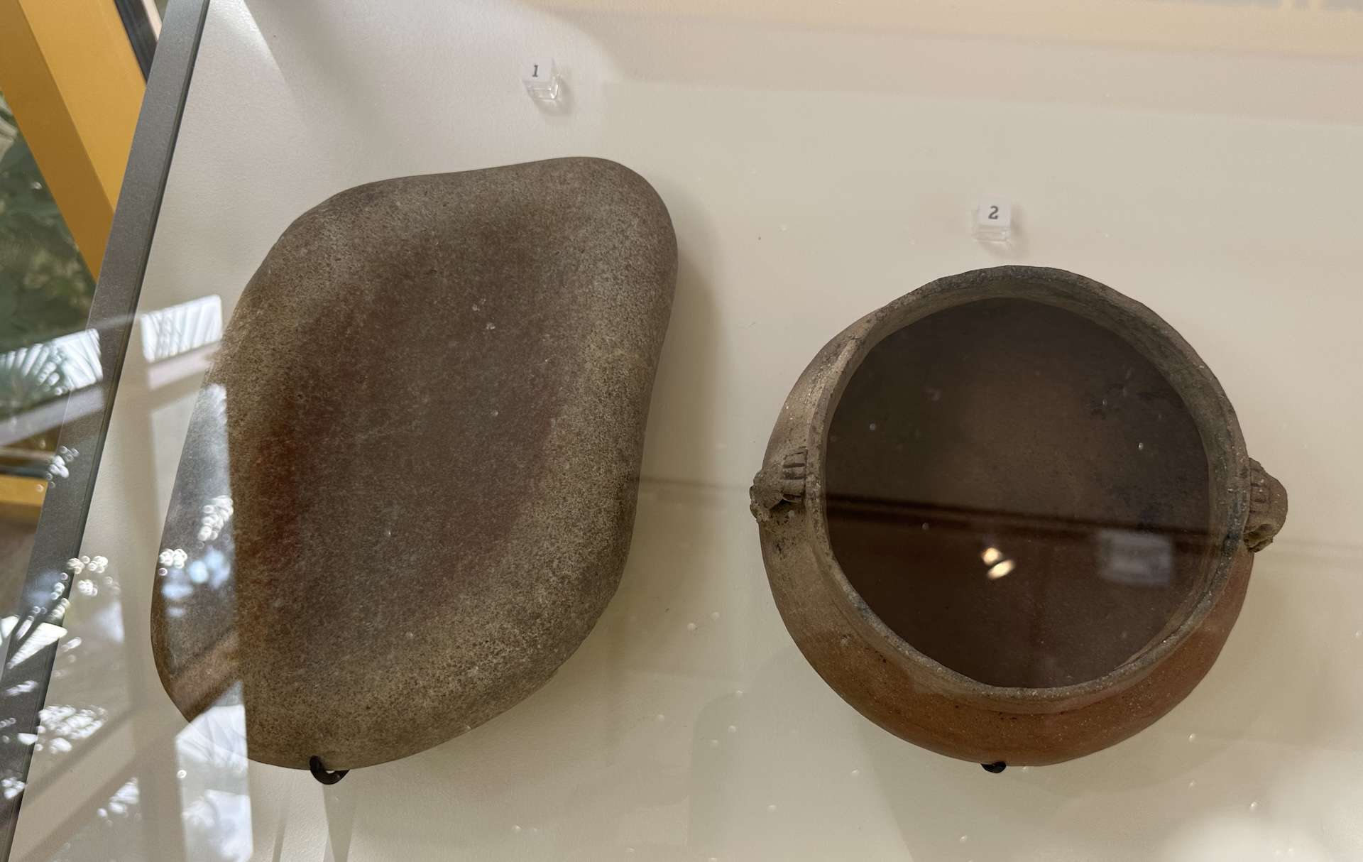 Pestle with a pigment stain (left) and jar (right); both from the Ceramic period at the National Archaeological Museum